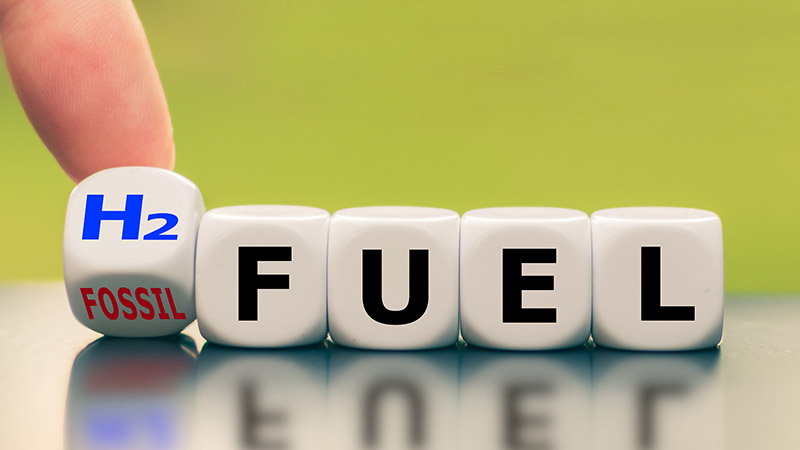 Hand changing blocks from fossil fuel to H2 fuel.