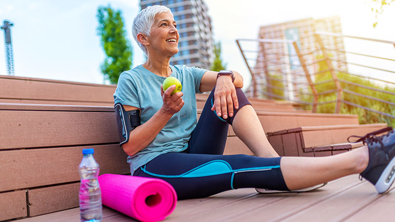 Woman relaxing next to a rolled-up yoga mat.